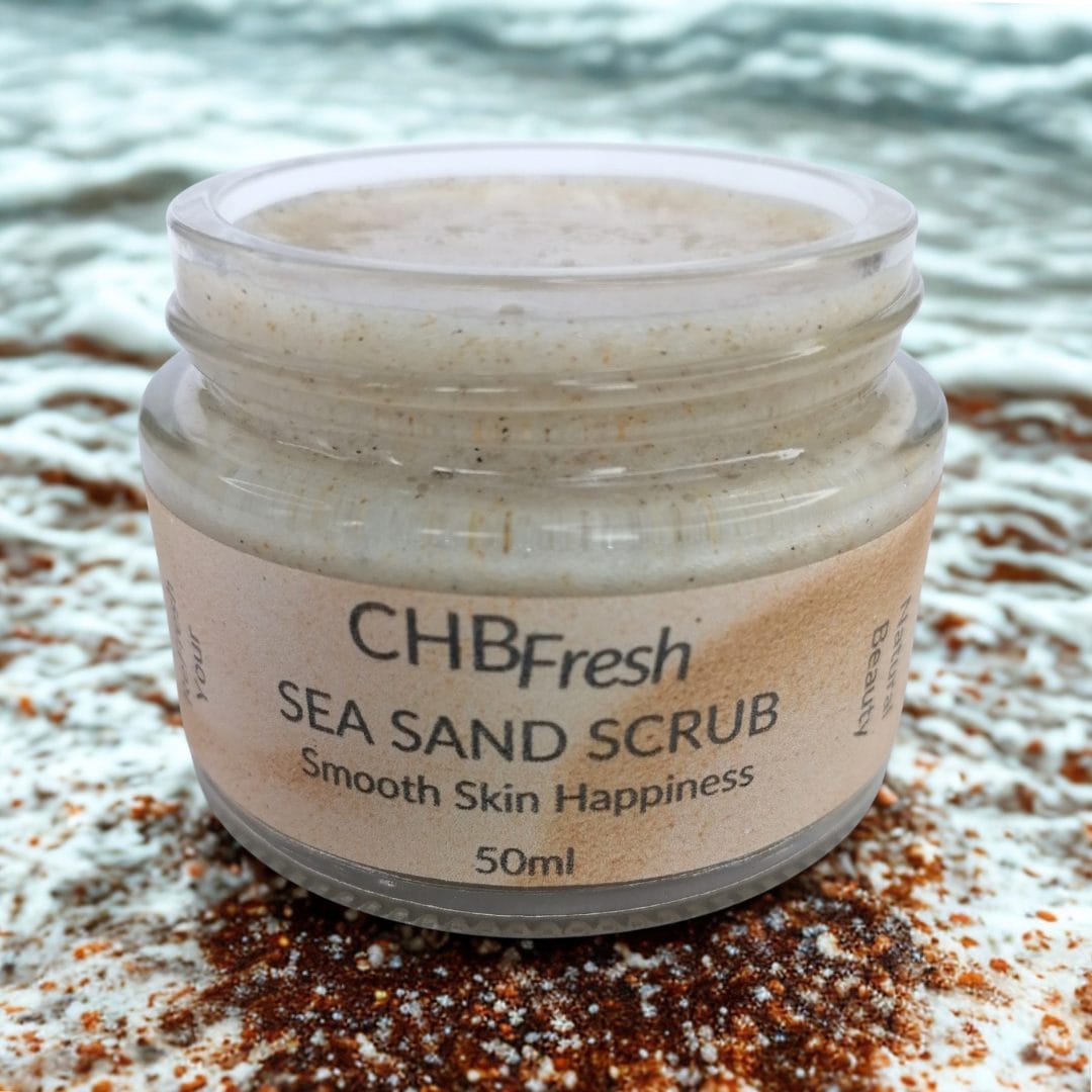 Sea Sand Scrub open jar on a sandy, frothy beach